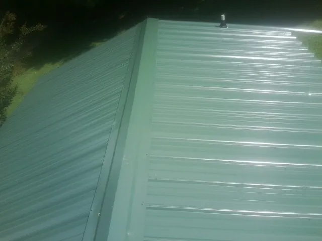 New green metal panels meeting at the ridge of a roof — Flat Roof Repair work by our crew in Bryant
