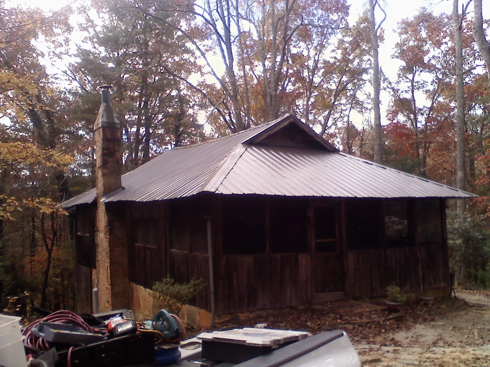 Brown metal hip roof on an old cabin with a stone chimney in Bryant